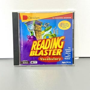 May include: A Reading Blaster Vocabulary CD-ROM for ages 9-12. The cover features a colorful graphic with the text "Reading Blaster Vocabulary" in large, bold letters. The CD-ROM case is in a clear plastic case.