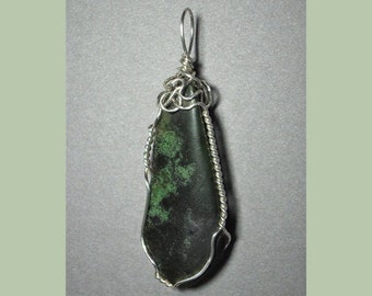 May include: A green stone pendant with silver wire wrapping. The stone is a dark green with lighter green markings.