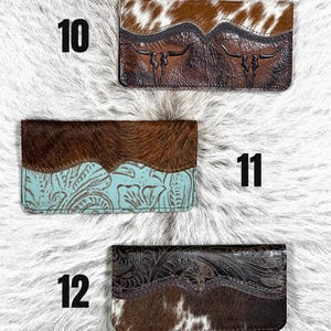 May include: Three rectangular wallets labeled 10, 11, and 12. Wallet 10 features brown and white cowhide with embossed longhorn skulls. Wallet 11 has dark brown cowhide and turquoise embossed leather. Wallet 12 displays dark embossed leather and brown cowhide.