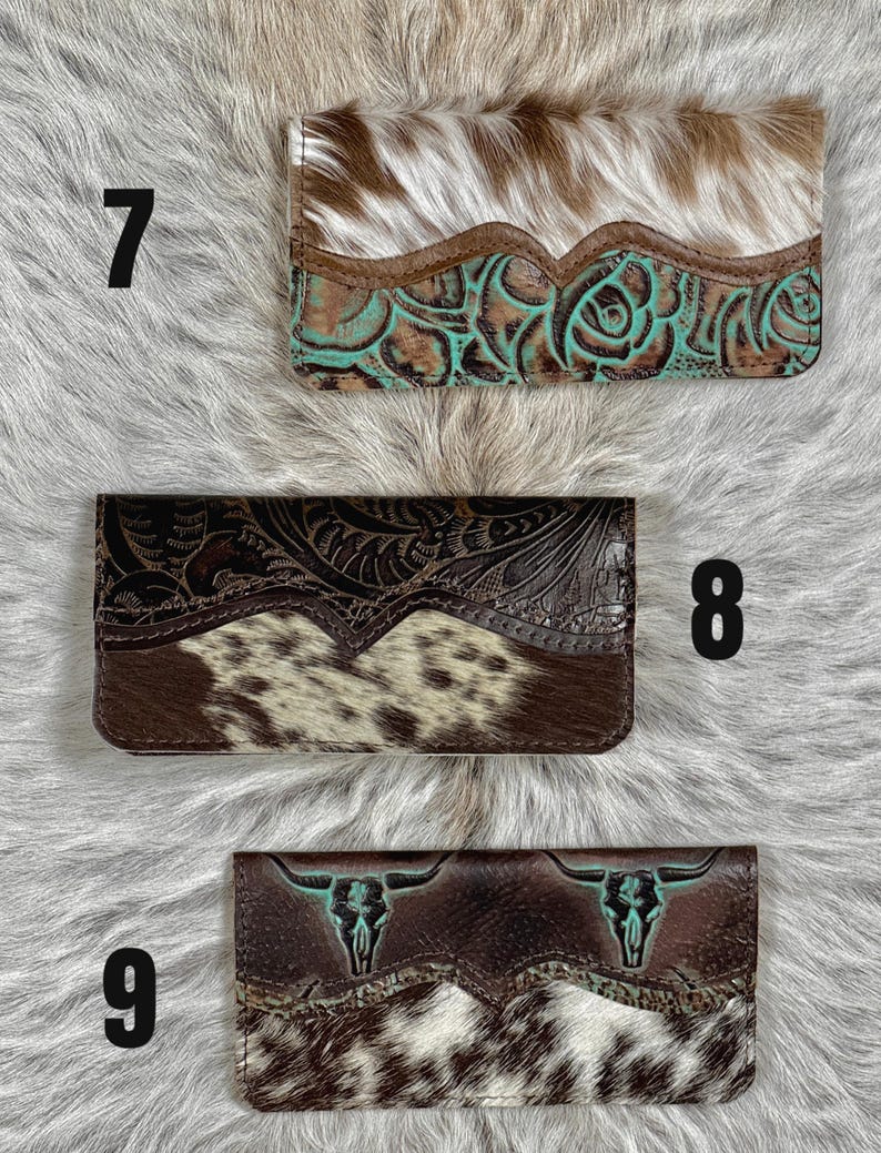 May include: Three rectangular wallets labeled 7, 8, and 9. Wallet 7 has white and brown cowhide with a turquoise floral embossed leather section. Wallet 8 features dark brown floral embossed leather and brown and white cowhide. Wallet 9 displays brown leather with two turquoise bull skull motifs and brown and white cowhide.