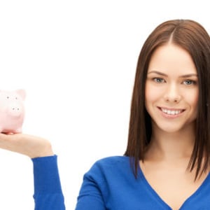 May include: A woman is holding a pink piggy bank in her right hand. She is smiling and looking at the camera.
