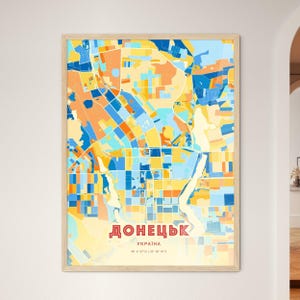 Puede incluir: Un mapa enmarcado de Donetsk, Ucrania, con un diseño abstracto colorido en tonos azules, naranjas y amarillos. El nombre de la ciudad está en rojo con escritura cirílica, con el nombre del país y las coordenadas debajo.