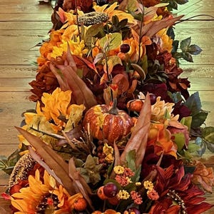 Puede incluir: Un camino de mesa de oto&ntilde;o con girasoles, calabazas, bayas y hojas en tonos naranja, rojo y marr&oacute;n.