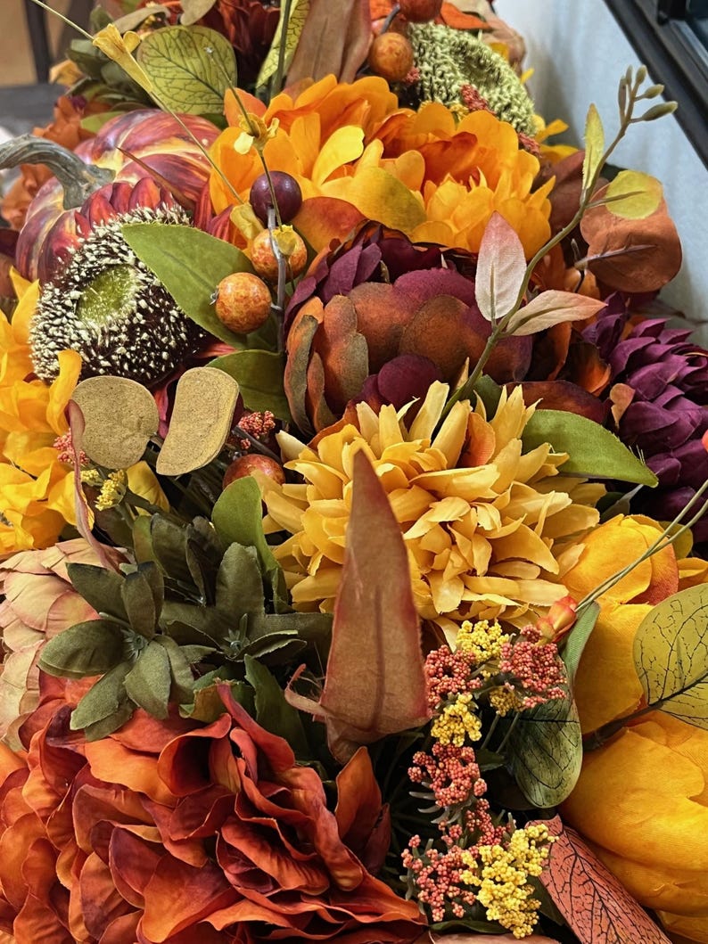 Puede incluir: Un arreglo floral de tem&aacute;tica oto&ntilde;al con una variedad de flores en tonos naranja, amarillo, rojo y marr&oacute;n. El arreglo incluye girasoles, crisantemos y otras hojas de oto&ntilde;o.