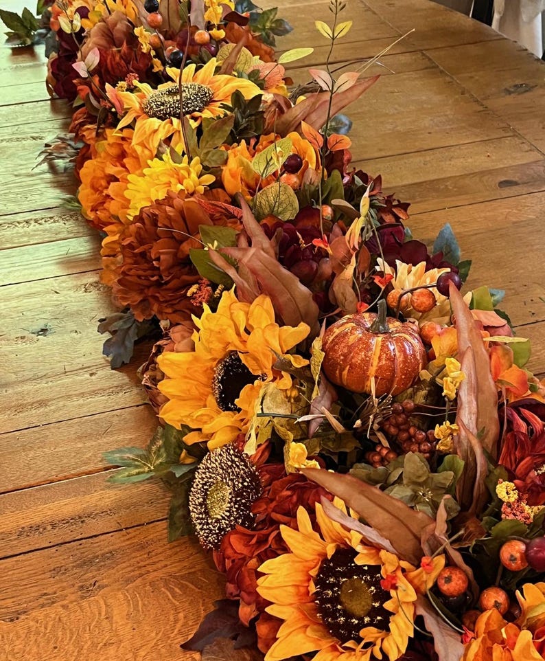 Puede incluir: Un camino de mesa de oto&ntilde;o con girasoles, calabazas, bayas y hojas en tonos naranja, amarillo, marr&oacute;n y rojo.
