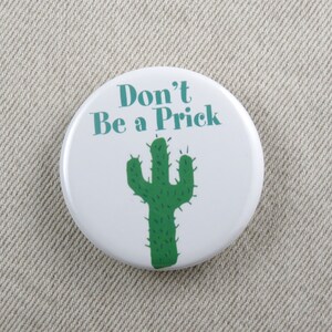 May include: White button with green cactus illustration and the text "Don't Be a Prick" in teal.