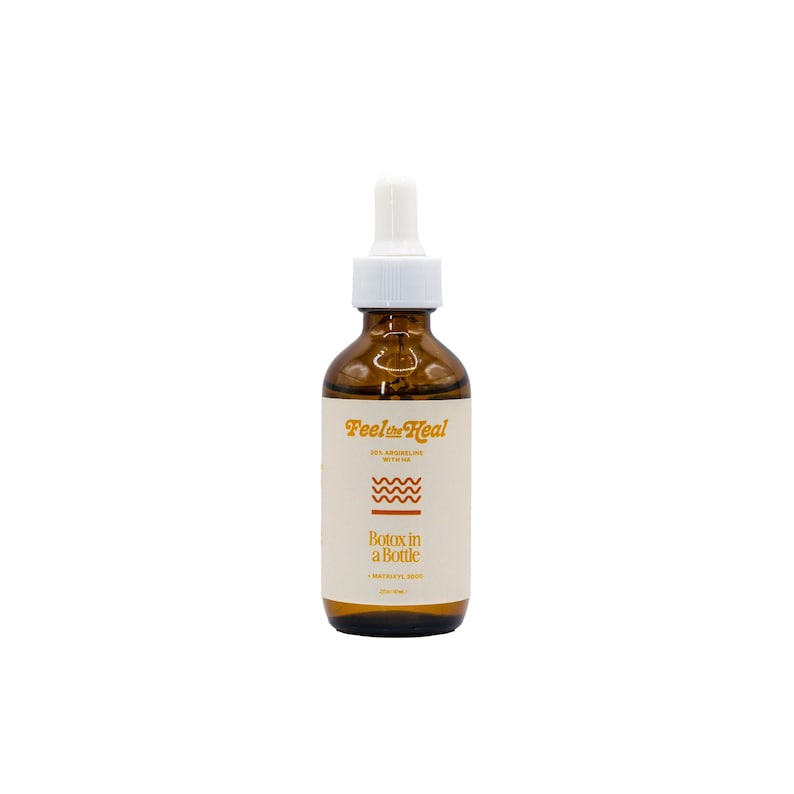 May include: A brown glass bottle with a white dropper top. The label reads "Feel the Heal" and "Botox in a Bottle". The label also features a wavy line design. The bottle contains a clear liquid.