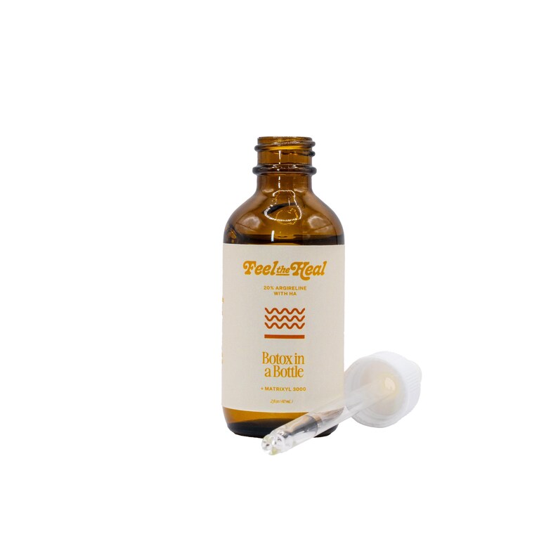 May include: A brown glass bottle with a white label and a dropper. The label reads "Feel the Heal" and "Botox in a Bottle." The dropper is clear with a white top. The bottle contains a liquid.