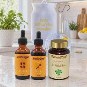 Puede incluir: Un kit de bienestar que incluye una bolsa de enema de silicona blanca con el texto In My Self Care Era, dos frascos cuentagotas de vidrio ámbar etiquetados Bye O Film y Take a Hike Parasite, y un frasco marrón con tapa dorada.