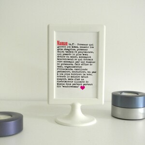May include: A white picture frame with a black and white text description of the word 'Maman' in French. The text reads: 'Maman (n.f.) Personne qui guerit les bobos, console les gros chagrins, personne multi taches et polyvalente, qui possede le plus beau metier du monde, accomplit benevolement ce qui devrait etre accompli par une dizaine de personnes, fait office de taxi, organisatrice d'evenements, excellente patissiere, couturiere, tou pas a les yeux derriere la tete, detecte le moindre bruit suspect, mais c'est un distributeur illimite de bisous doux partout partout dit 'wonderwoman''