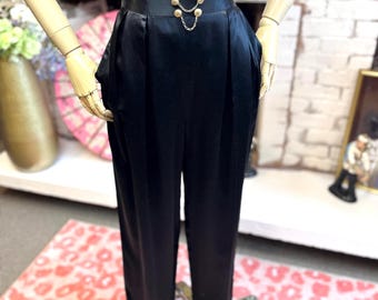 Pantalones de satén negro de los años 80: detalle de cadena dorada y pliegues en la parte delantera