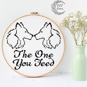 May include: Black and white cross stitch pattern of two wolves facing each other with the text "The One You Feed".