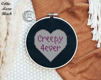May include: A black embroidery hoop with a gray heart-shaped design that says "Creepy 4ever" in purple lettering.