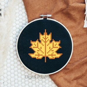 May include: A black embroidery hoop with a yellow pixelated leaf design. The text "Celtic Moon Black" and "Digital Pattern" are visible below the hoop.