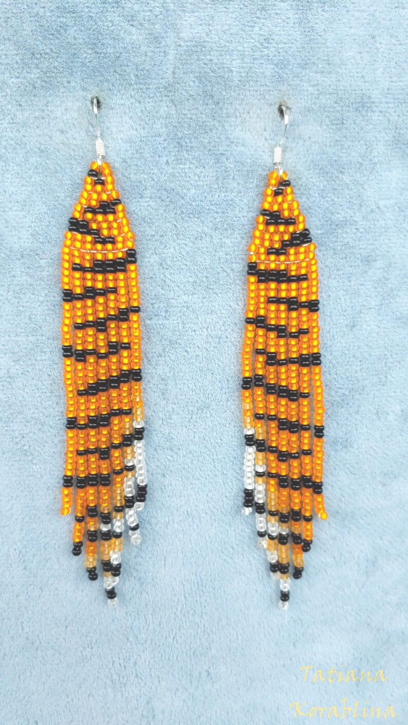 May include: A pair of long, beaded earrings with a tiger stripe pattern in orange, black, and white.
