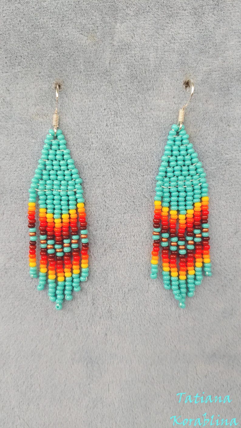 May include: A pair of turquoise and orange beaded earrings with silver hooks. The earrings are made with small seed beads and feature a geometric pattern.