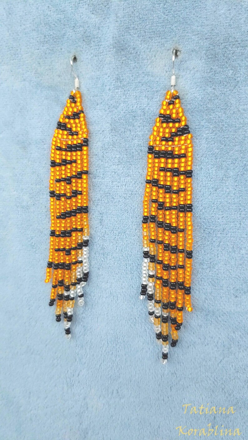 May include: A pair of long, beaded earrings with a tiger stripe pattern in orange, black, and white.