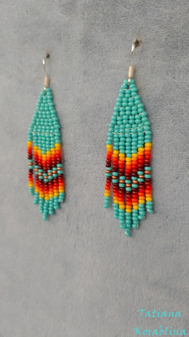 May include: A pair of turquoise, red, orange and yellow beaded earrings. The earrings are long and dangle, with a silver hook.