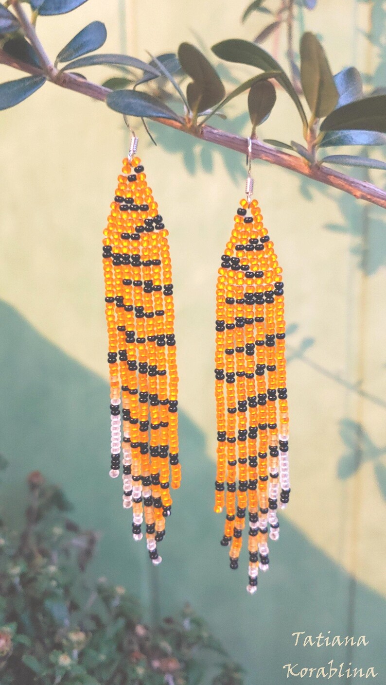 May include: A pair of long, beaded earrings with a tiger stripe pattern in orange, black, and white.