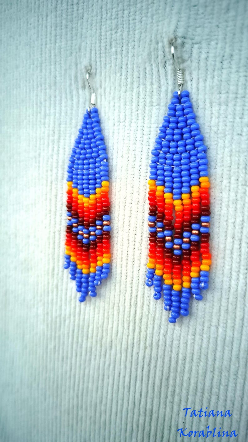 May include: A pair of blue, orange, red and yellow beaded earrings. The earrings are teardrop shaped and have a geometric pattern.