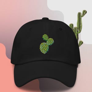 Könnte beinhalten: Eine schwarze Baseballkappe mit einem gestickten grünen Kaktus-Design. Der Kaktus hat weiße Akzente und befindet sich in der Mitte der Kappe.