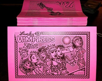 May include: Pink and black zine with the title "Lucky 13 Vampress Zine" and an illustration of a group of people with dark hair and clothing. The illustration is in a comic book style.