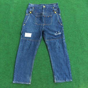 May include: A pair of blue denim carpenter jeans with yellow stitching and a small white label on the right leg.