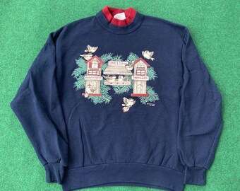 May include: A navy blue sweatshirt with a festive design featuring a bird feeder with birds and three birdhouses. The birdhouses have the text "Stocks & Things" and "Twigs & Gifts".
