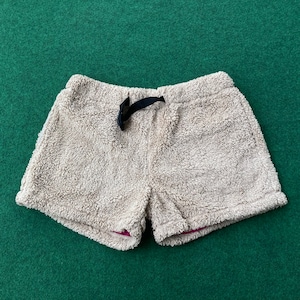May include: Beige fleece shorts with a black drawstring tie. The shorts have a fuzzy texture and a pink lining.