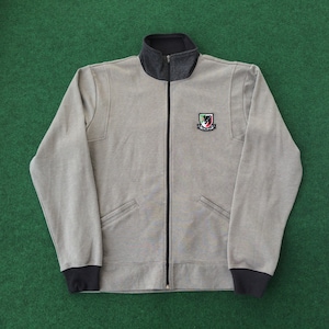 May include: A gray zip-up sweatshirt with black trim and a small embroidered patch on the chest. The patch features a lion with a shield and the text "We Are All Lions".
