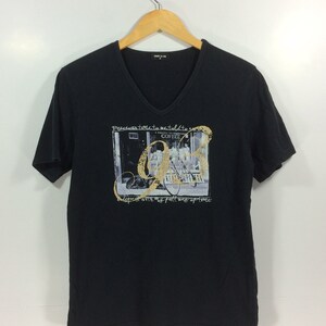 Puede incluir: Camiseta negra de manga corta con un estampado gráfico de una cafetería con una bicicleta en frente. El texto en la camiseta dice "Precious time to refill to my cup with my full bag of time".