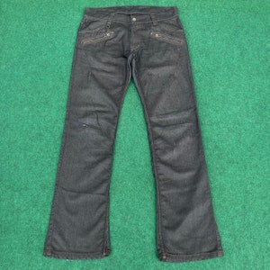 May include: Dark wash denim jeans with multiple zippered pockets on the front and back. The jeans have a bootcut style.