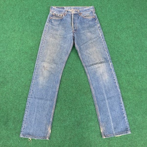 May include: A pair of blue denim jeans with a faded look. The jeans have a classic five-pocket style and a straight leg.