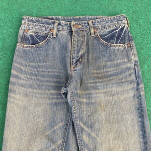 May include: A pair of blue denim jeans with a faded look. The jeans have a classic five-pocket style and a button fly.