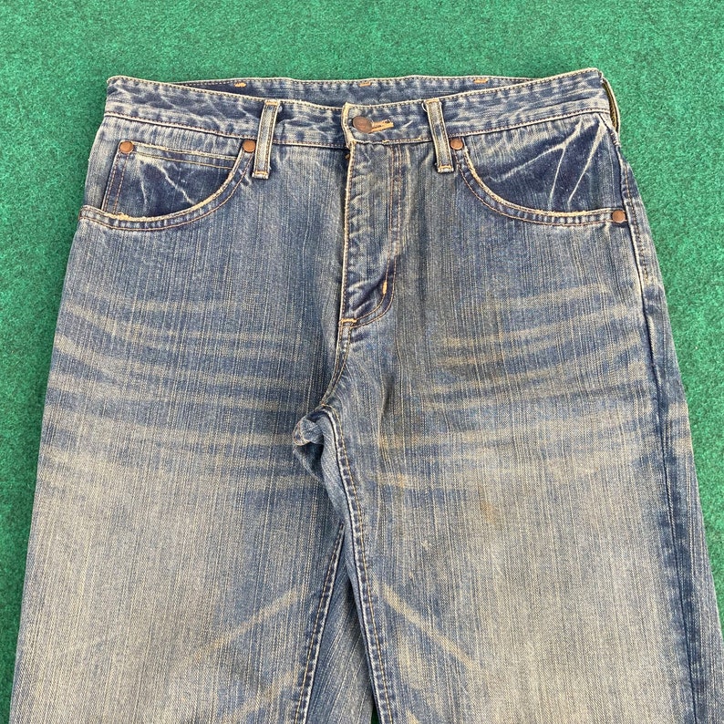 May include: A pair of blue denim jeans with a faded look. The jeans have a classic five-pocket style and a button fly.