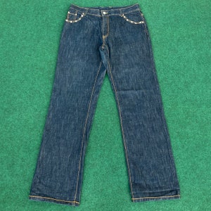 May include: A pair of dark blue denim jeans with yellow stitching and a decorative design on the back pockets.
