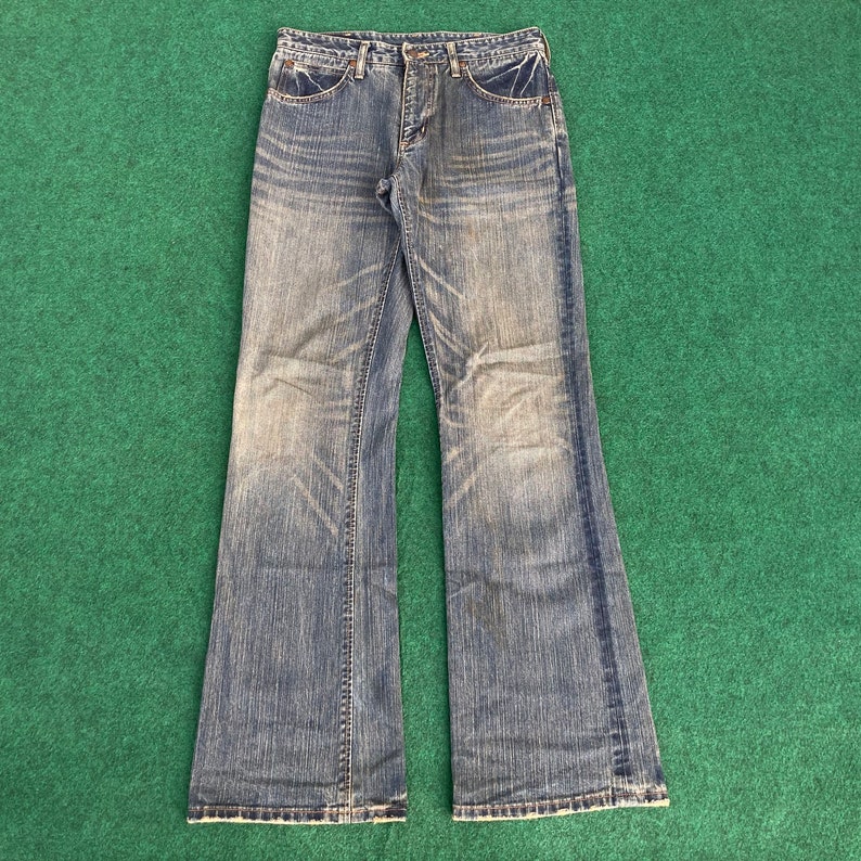 May include: A pair of blue denim jeans with a bootcut style. The jeans have a faded look and are made of a soft, comfortable fabric.