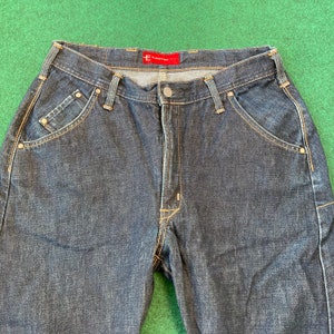 May include: Dark blue denim jeans with a red "E*Thirteen" label on the waistband. The jeans have a relaxed fit and multiple pockets.