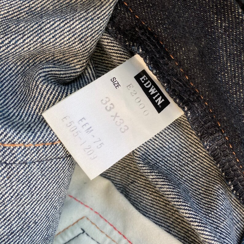 May include: A white tag with black text that reads "EDWIN" and "E-2000" with a size tag that reads "33 x 33" and "E.M-75 E-503-1201".