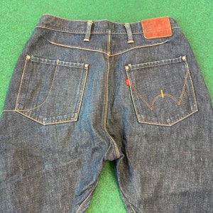 May include: A pair of dark blue denim jeans with a brown leather patch on the back waistband that says "Functional Control".