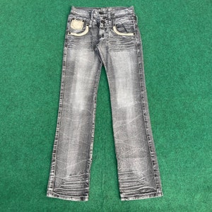 Könnte beinhalten: Graue Jeans aus Denim mit ausgewaschenem Look und dekorativen Nähten an den Taschen.