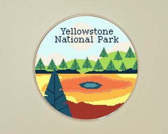 May include: A circular design featuring a stylised landscape of a geyser in Yellowstone National Park. The geyser is surrounded by green trees and a blue sky with a white sun.