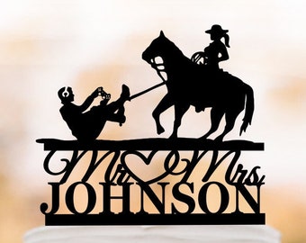 May include: Black silhouette cake topper of a bride and groom riding a horse. The groom is being dragged behind the horse. The topper says "Mr & Mrs JOHNSON"