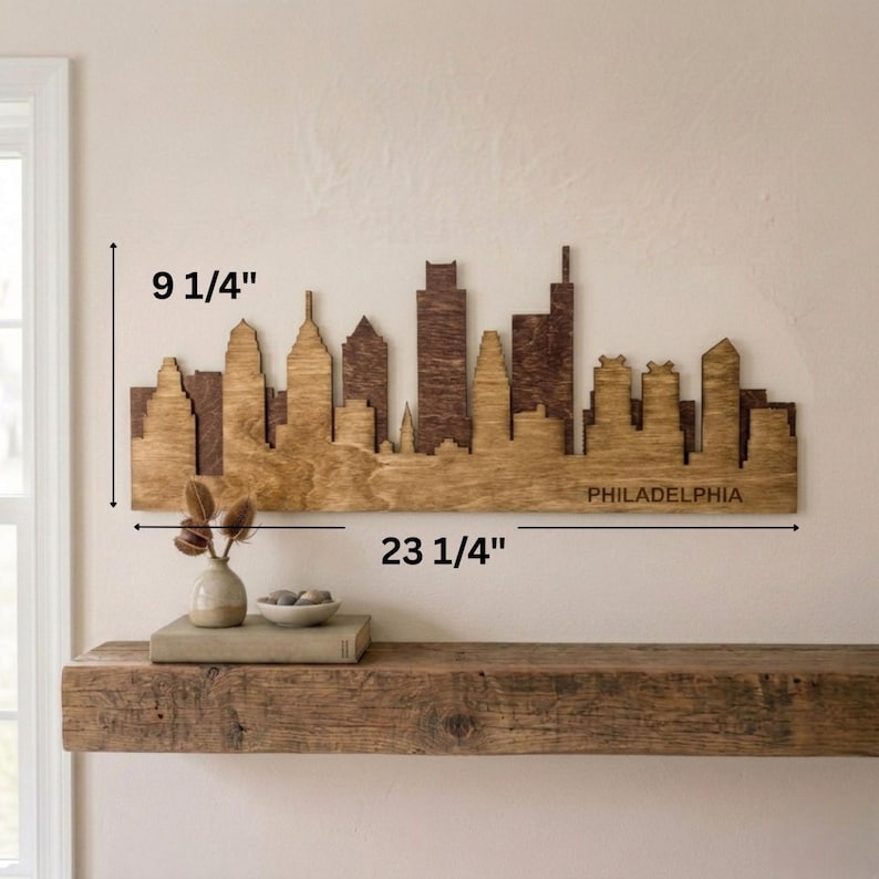 Puede incluir: Arte mural de madera con la silueta de Filadelfia, que mide 59 cm de ancho y 23,5 cm de alto. La silueta est&aacute; cortada con l&aacute;ser en madera, con un dise&ntilde;o marr&oacute;n de dos tonos. La palabra "PHILADELPHIA" est&aacute; grabada en la parte inferior.