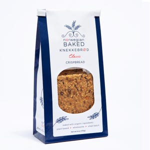 May include: A white and dark blue bag of Norwegian Baked Knekkebr&oslash;d Classic crispbread. The packaging features a circular window revealing the textured, seed-filled crackers inside. Text includes "norwegian BAKED KNEKKEBR&Oslash;D" and "Net wt 6 oz (170g)".