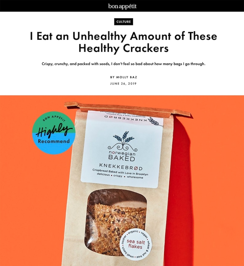 May include: A brown paper bag of Norwegian Baked Knekkebr&oslash;d crispbread with a clear window showing seeded crackers. The label features the text Norwegian Baked, Knekkebr&oslash;d, and sea salt flakes. A blue circular badge reads Bon App&eacute;tit Highly Recommend.