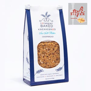 May include: A white and dark blue paper bag of Norwegian Baked Knekkebr&oslash;d Sea Salt Flakes crispbread. The front features a circular window showing the textured, seeded cracker, with text including 'baked with organic ingredients' and 'Net wt 6 oz'.