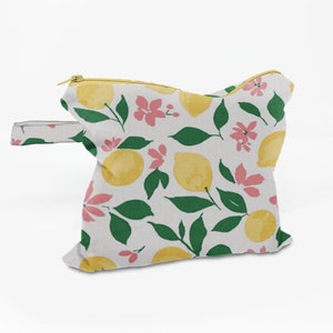 May include: A white zippered pouch with a yellow handle. The pouch has a lemon and floral print in shades of yellow, green, and pink.