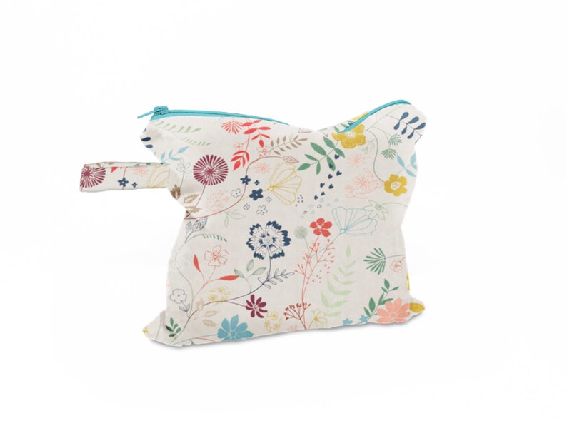 May include: A white zippered pouch with a floral print in shades of pink, red, blue, yellow, and green. The pouch has a turquoise zipper and a handle.