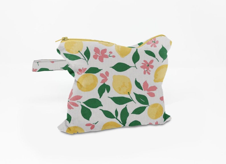 May include: A white zippered pouch with a yellow handle. The pouch has a lemon and floral print in shades of yellow, green, and pink.